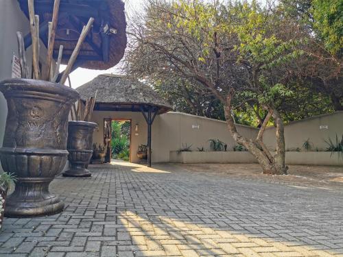 a brick walkway with two large vases next to a building at Aerotropolis Guest Lodge in Kempton Park
