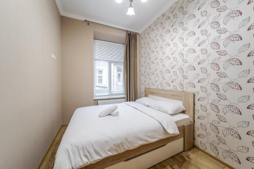 a small bedroom with a bed and a window at Apartment on Stavropihiiska Street 1 in Lviv