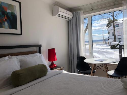 Un dormitorio con una cama y una mesa y una ventana. en Domaine Belle Plage, en Baie-Saint-Paul