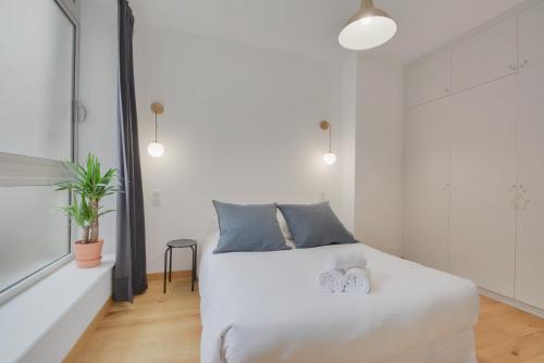 une chambre avec un lit blanc avec des oreillers bleus dans l'établissement L'Essentiel de Stanislas, à Nancy