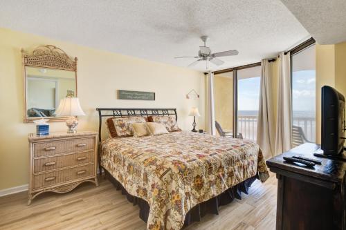 een slaapkamer met een bed, een spiegel en een televisie bij Charleston Oceanfront Villas in Folly Beach