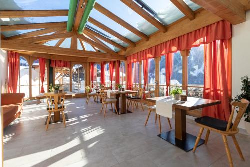 pokój ze stołami, krzesłami i oknami w obiekcie Pitztal Living Apartments w mieście Jerzens