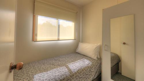a small bedroom with a bed and a window at Airport Tourist Village Melbourne in Melbourne