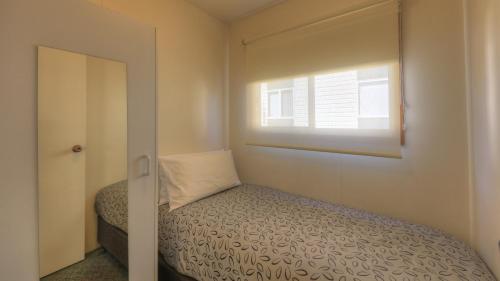 a small bedroom with a bed and a window at Airport Tourist Village Melbourne in Melbourne
