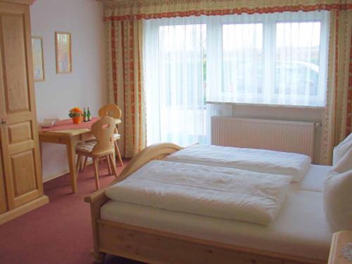 Un dormitorio con una cama y una mesa y una ventana. en Pension Irene Nist, en Bad Birnbach