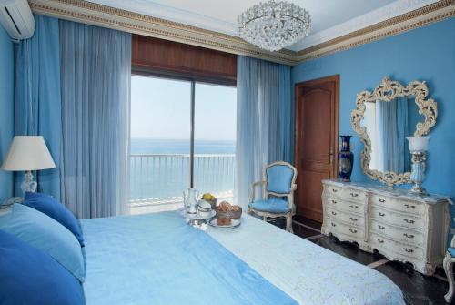 1 dormitorio azul con 1 cama grande y espejo en BarcelonaVacances-La Mansión, en Sant Pol de Mar