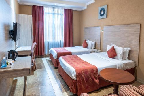 a hotel room with two beds and a table at Hotel Waterbuck in Nakuru