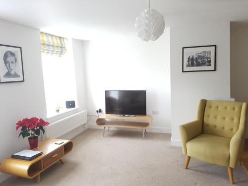 a living room with a television and a chair at Warwick Market Place Apartment in Warwick
