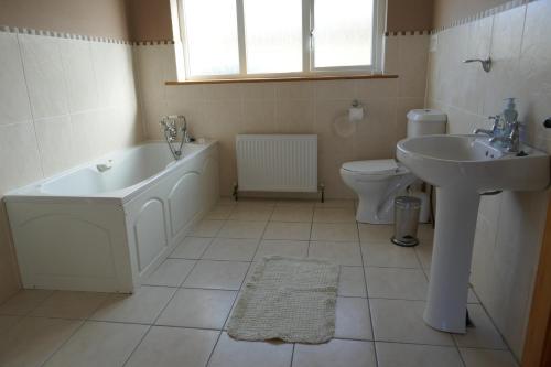 uma casa de banho com uma banheira, um lavatório e um WC. em Cois Farraige em Doolin