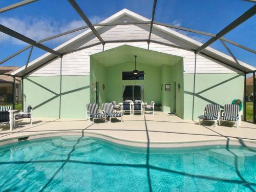 a house with a swimming pool with chairs and a table at The Oasis in Orlando