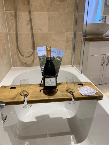 una bottiglia di vino e due bicchieri su una vasca da bagno di The Stowe a Shrewsbury