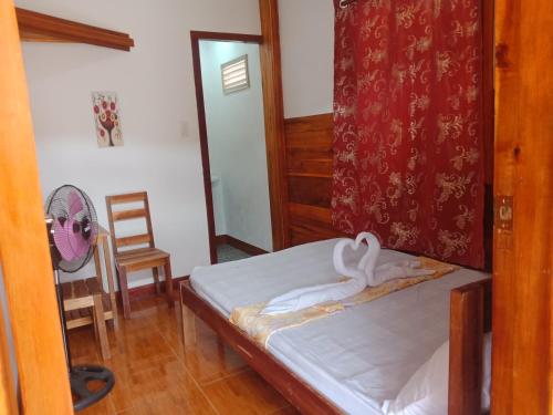 1 dormitorio con 1 cama, 1 silla y ventilador en D' Angels Inn, Port Barton, en San Vicente