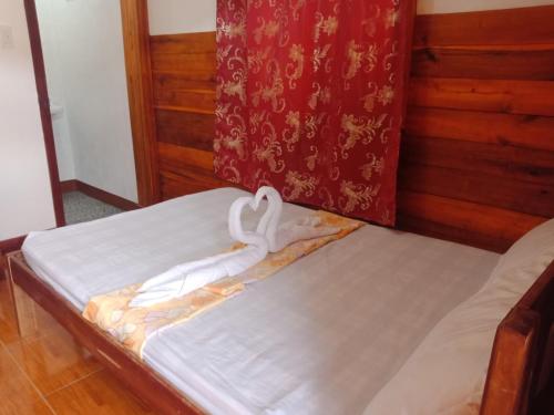 a bed with a white ribbon on it at D' Angels Inn, Port Barton in San Vicente
