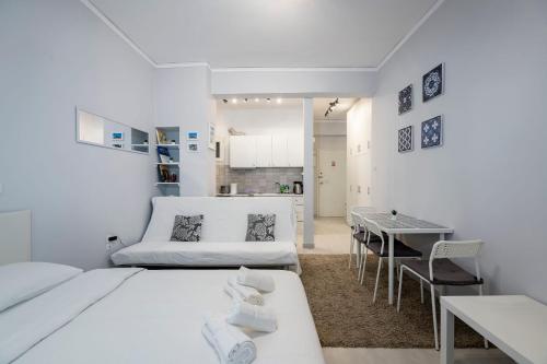biały pokój z 2 łóżkami i stołem w obiekcie Beautiful studio at Panathenaic Stadium w Atenach