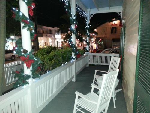 a porch decorated for christmas with white chairs and christmas lights at Duval House in Key West