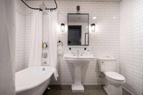uma casa de banho branca com um lavatório, um WC e uma banheira em Cantilever Hotel, Trademark Collection by Wyndham em Ranier