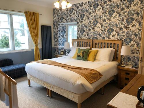 a bedroom with a large bed with blue and white wallpaper at Dalgreine Guest House in Blair Atholl