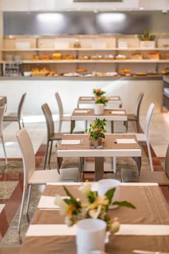 a restaurant with tables and chairs with flowers on them at Alfa Fiera Hotel in Vicenza