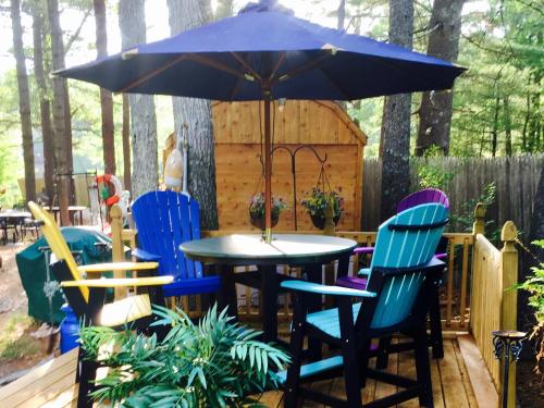 a table and chairs under an umbrella on a deck at Clear Pond Getaway in Plymouth