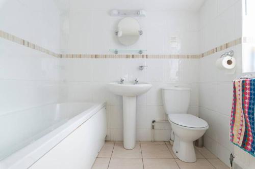a white bathroom with a sink and a toilet at Jims Cottage in Holt