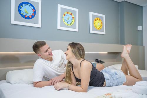 a man and a woman laying on a bed at Hotel Morada do Sol in Caldas Novas