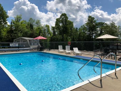 a swimming pool at a resort with chairs and umbrellas at Lakeview Motel in Haliburton