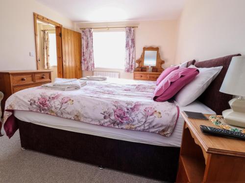 a bedroom with a large bed with a pink blanket at Jess Cottage in Skipton