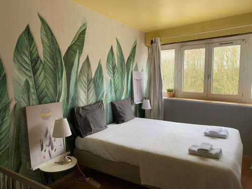 a bedroom with a bed with leaves painted on the wall at F3 - Séjour Paris + Disneyland - 37bd Segrais Lognes in Lognes