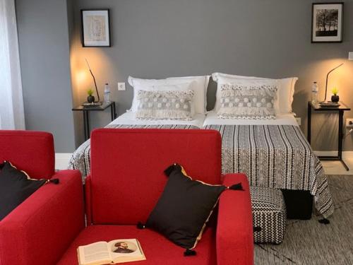 a bedroom with a bed and two red chairs at BUS STATION Suites & Studios in Coimbra