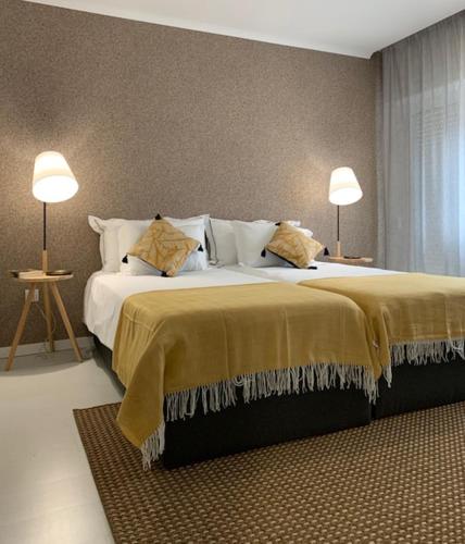 a bedroom with a large bed with two lamps at BUS STATION Suites & Studios in Coimbra