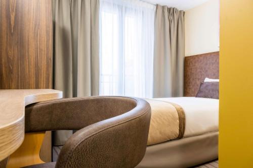a hotel room with a bed and a chair and a window at Quality Hotel Toulouse Centre in Toulouse