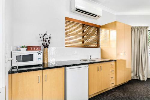 a kitchen with a sink, stove, microwave and refrigerator at Comfort Inn Parklands Calliope in Calliope