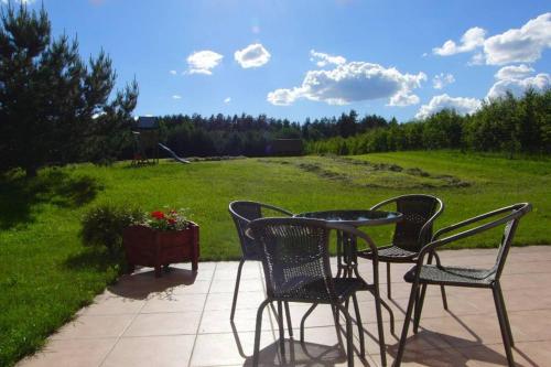 a patio with chairs and a table and a field at Dom pod Dziką Gruszą in Piecki