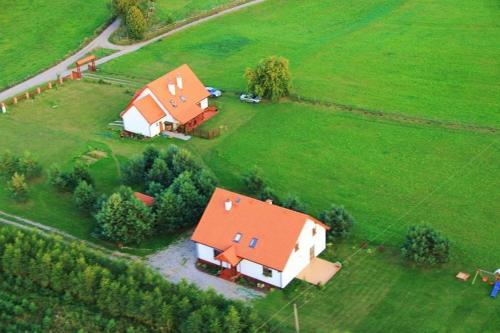 a house with an orange roof in a green field at Dom pod Dziką Gruszą in Piecki