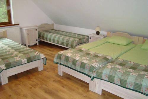 three beds in a room with wooden floors at Dom pod Dziką Gruszą in Piecki