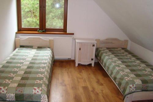 two beds in a room with two windows at Dom pod Dziką Gruszą in Piecki
