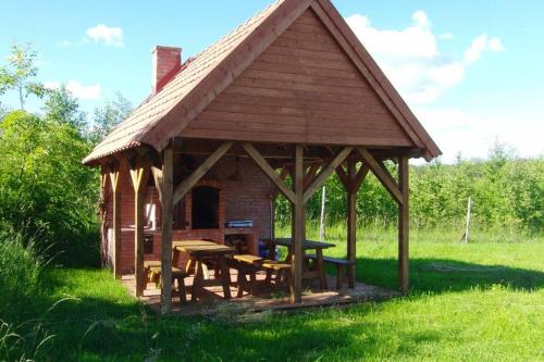 a wooden gazebo with a picnic table in a field at Dom pod Dziką Gruszą in Piecki