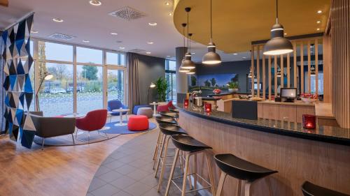 a bar in a restaurant with red and blue stools at Holiday Inn Express Düsseldorf - City North by IHG in Düsseldorf