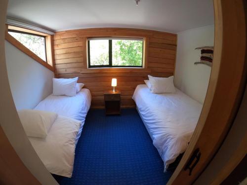 two beds in a small room with two windows at Las Bravas Lodge in Las Trancas