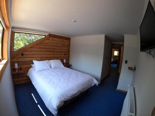 a bedroom with a large white bed with a window at Las Bravas Lodge in Las Trancas