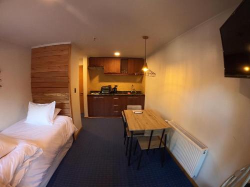 um quarto com uma cama, uma mesa e uma cozinha em Las Bravas Lodge em Las Trancas
