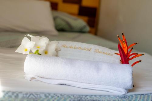 a towel with flowers sitting on top of a bed at Pousada Barros in Jericoacoara
