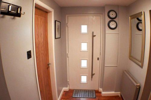 a hallway with a door and a clock on the wall at The Den Studio Apartment - Withernsea in Withernsea