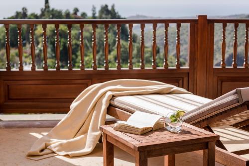 a wooden bench with a blanket and a book on a table at Casa León Royal Retreat in Maspalomas