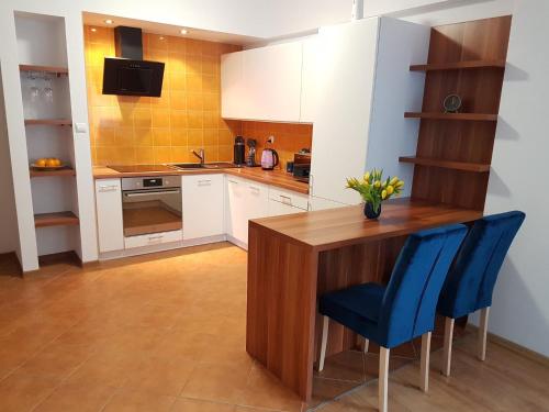 a kitchen with a wooden table and blue chairs at Apartament h2o in Giżycko