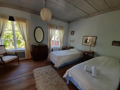 a bedroom with two beds and a mirror and a chair at Frägsta Hälsingegård B&B in Näsviken