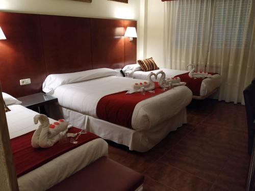 una habitación de hotel con 3 camas con animales de juguete. en Pensión El Otero en Guadalajara