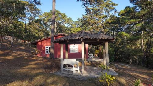 a small red house with a chair in front of it at Cabañas Bosque llano de la Virgen in Intibucá