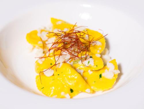 a plate of food with yellow vegetables on a white plate at Castello Montegiove in Fano