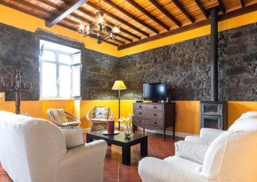 a living room with white chairs and a tv at Casa da Fazenda (Mountain View) in Conceição